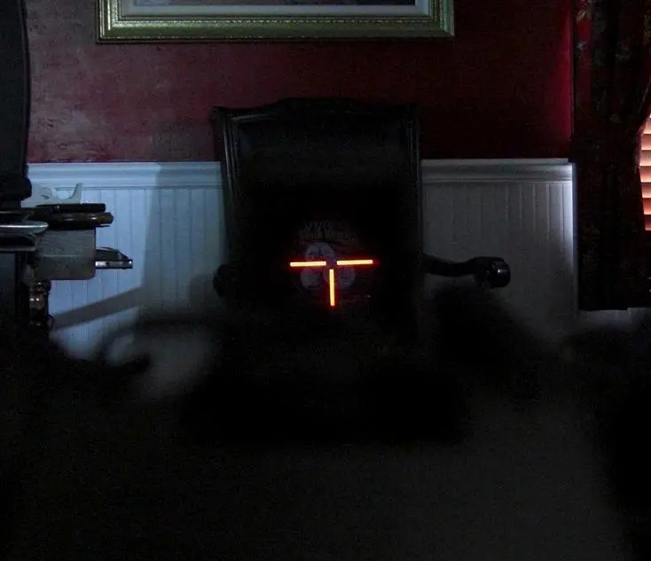 A weapon targeting a black chair in a dark room
